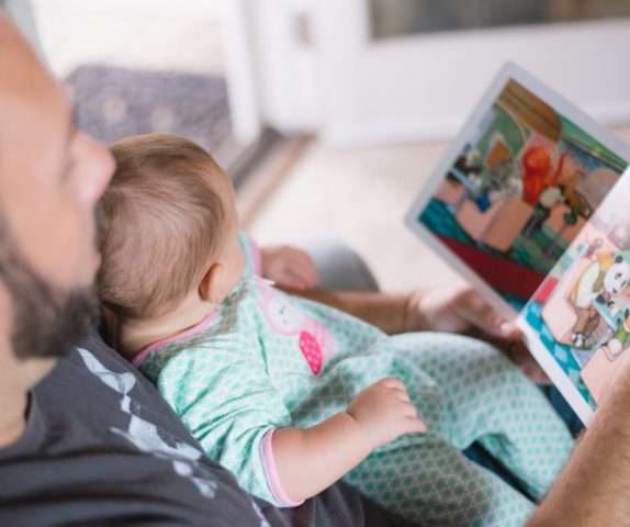 pai lendo história infantil para o filho em seu colo